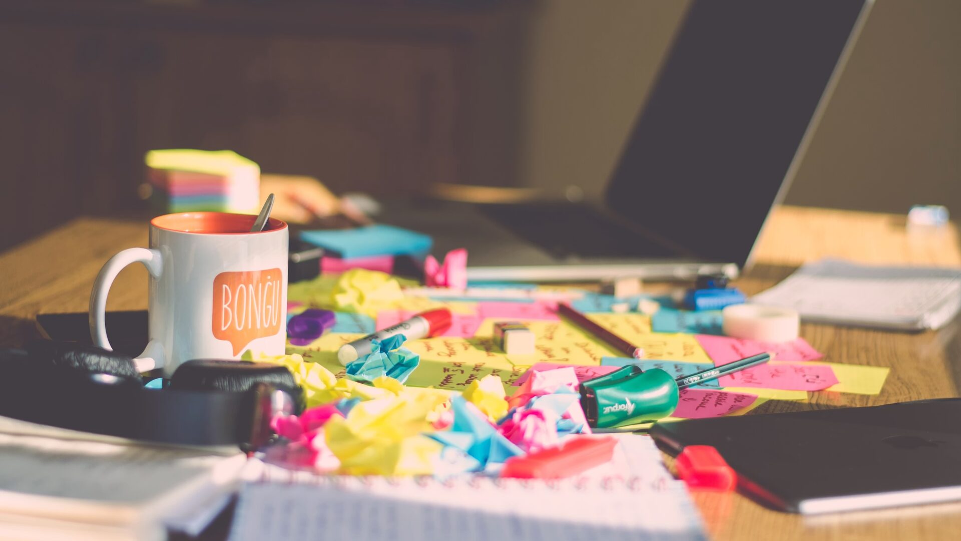 A cup on a table full of post-its.